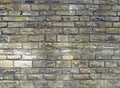 Old exterior wall made of blocks of rough yellow brown grit stone