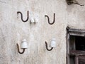 Old facade of an abandoned building where four iron hooks stand out from the wall and two porcelain insulators that are already un