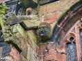 An old face and head carved in sandstone on the exterior of St Oswald`s Parish Church in Malpas, Cheshire, UK.
