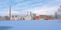 Old factory buildings and chimney along a snow covered park