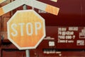 Old faded stop sign with a cross in front of a train wagon