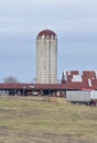 Old farm grain silo sits weathering near barns