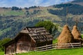 An old farmer's wooden house stands on an elephant mountain near a haystack against the backdrop of mountain peaks Royalty Free Stock Photo