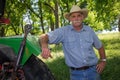 Old Farmer Stands by Tractor