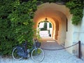 Old fashion bycicle lean againt a flowered wall with green ivy, near a tunnel porch Royalty Free Stock Photo