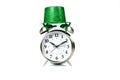 Old fashioned alarm clock wearing a green sparkly hat over white