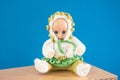 Old Fashioned baby Doll dressed in knitted costume sits on shelf on blue background