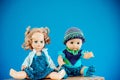 Old-Fashioned baby Doll dressed in knitted costume sits on shelf on blue background