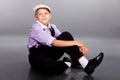 Old fashioned boy sitting on gray background Royalty Free Stock Photo