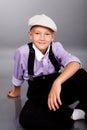 Old fashioned boy sitting on gray background Royalty Free Stock Photo