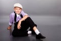 Old fashioned boy sitting on gray background Royalty Free Stock Photo