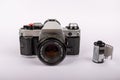 Old-fashioned camera aligned at the center of a white surface, accompanied by 35mm film rolls Royalty Free Stock Photo