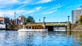 Old fashioned Canal Boat going under the bridge at the Stationsplein at Central Station in the center of Amsterdam Royalty Free Stock Photo