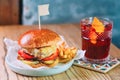 Old fashioned cocktail and fat burger with meat, cheese, tomato, pickle and french fries