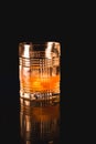 Old Fashioned cocktail in a rocks glass on a black reflective surface