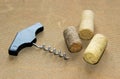 An old-fashioned corkscrew and three used corks on embossed surface. Selective focus