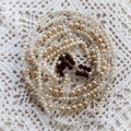 Old fashioned crochet doily with beaded necklaces placed on top.