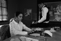 Old fashioned detective and her colleague working in office. Black and white effect Royalty Free Stock Photo