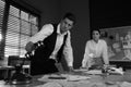 Old fashioned detective and his colleague working in office. Black and white effect Royalty Free Stock Photo