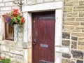 Old-fashioned front door with hanging basket on exterior of stone house wall Royalty Free Stock Photo