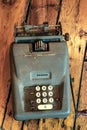 Old fashioned green adding machine on wood slat table