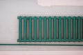 Old-fashioned green heating radiator on a grey tile wall. Indoor heating system Royalty Free Stock Photo