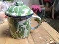 An old-fashioned green motif cup, on a brown wooden table