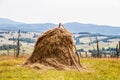 Old fashioned hay stack surrounded by stick fence with farm and hill countryside in the background - Georgia Eastern Europe Royalty Free Stock Photo