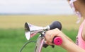 Old fashioned horn with chrome trumpet and black rubber bulb close-up mounted on a children`s bike. Little girl in a Royalty Free Stock Photo