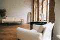 Old fashioned interior big wooden window and mirror, white sofa in old vintage living room with brick walls Royalty Free Stock Photo