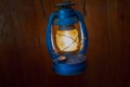 Old fashioned lantern with flame on a brown wooden wall Royalty Free Stock Photo