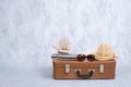Old fashioned leather travel bag with summer marine accessories: glasses, straw beach hat, toy sailboat on grey background. Banner Royalty Free Stock Photo
