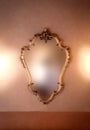 Old fashioned luxury gold colored frame mirror antique design, hanging on vintage wall background texture, blurred Royalty Free Stock Photo