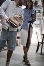 Old-fashioned man carrying heavy pile of books at library, looking at female with her cell phone in her hands with e-books Royalty Free Stock Photo