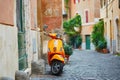 Old fashioned orange motorbike on a street of Trastevere district, Rome