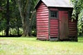 Old fashioned painted outhouse on back lawn near woods Royalty Free Stock Photo