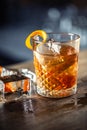 Old fashioned rum drink on ice with orange zest garnish