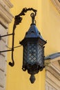 Old-fashioned street wall lamp made of black metal. Gray facade of an old house with a window and a wooden frame. Lviv, Ukraine Royalty Free Stock Photo