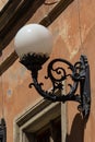 Old-fashioned street wall lamp made of black metal. Gray facade of an old house with a window and a wooden frame. Lviv, Ukraine Royalty Free Stock Photo