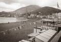 Old-fashioned style faded image at beach of Riomaggiore with beach-side buildings, flags and surrounding hills