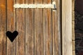 Old fashioned toilet door with carved heart shape. Weathered wooden door with heart shaped peephole