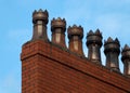 Old fashioned traditional clay chimney pots on a red brick support against a blue sky Royalty Free Stock Photo