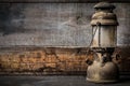 Old fashioned vintage kerosene oil lantern lamp burning with a soft glow light with aged wooden floor Royalty Free Stock Photo