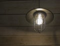 Old fashioned vintage lantern lamp burning with a soft glow light in an antique rustic country barn with aged wood wall Royalty Free Stock Photo