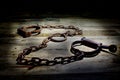 Old fashioned, vintage shackles on a rustic wooden background.