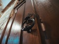 Old-fashioned vintage steel knocker handle on old wooden door close up Royalty Free Stock Photo