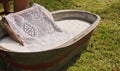 An old fashioned washing trougth filled with water, a vintage washboard and soap that wash the laundry