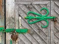 Old fashioned wooden door with decorative hinge and rusty padlock. closeup view