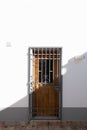 Old fashioned wooden door with a metal security grill half in bright sunlight half in shade Royalty Free Stock Photo