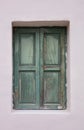 Old fashioned worn window with green wooden shutters, closed, on painted wall background